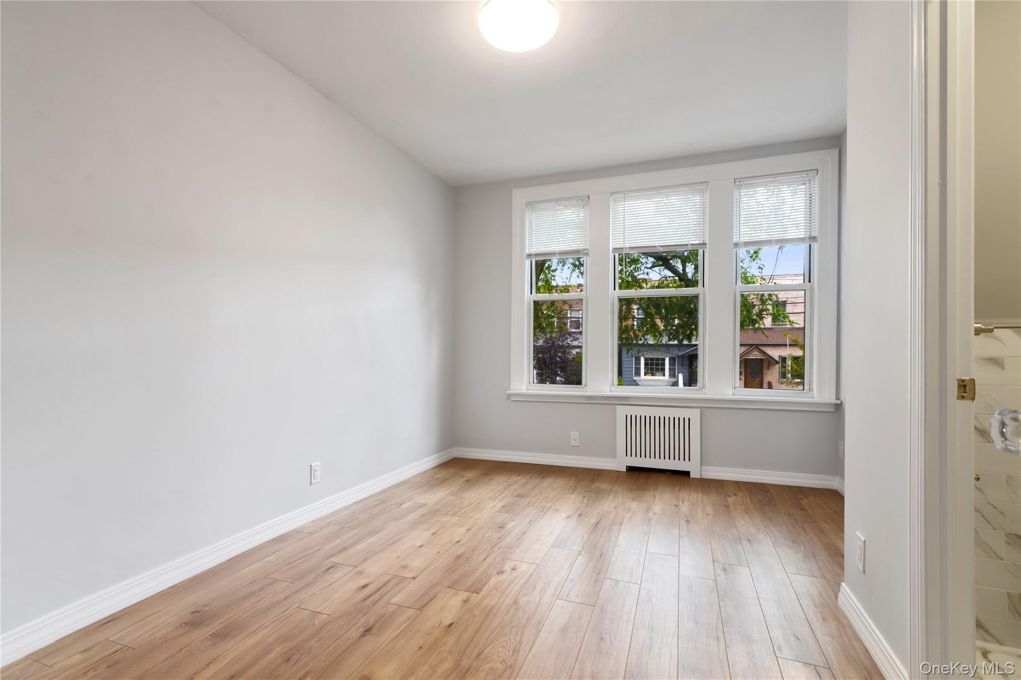 21-69 45th Street, Unit 3 Queens, NY 11105 - Photo 12 of 31 an empty room with wooden floor and windows