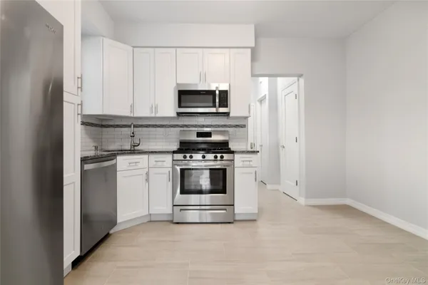 a kitchen with white cabinets and stainless steel appliances