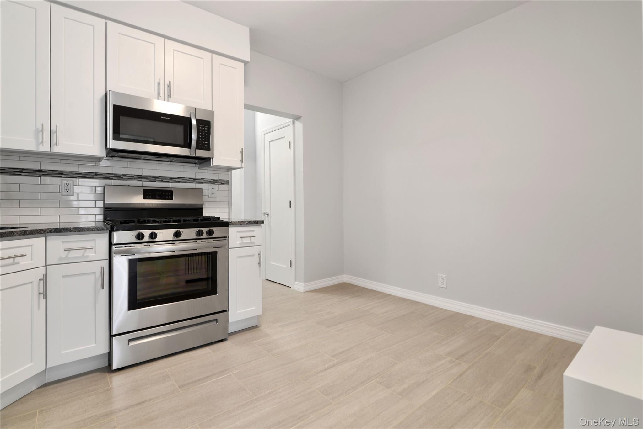 21-69 45th Street, Unit 3 Queens, NY 11105 - Photo 20 of 31 a kitchen with granite countertop a stove and a microwave