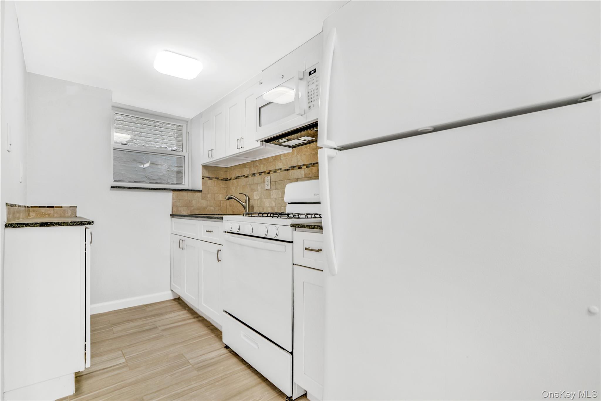 21-69 45th Street, Unit 3 Queens, NY 11105 - Photo 22 of 31 a kitchen with white cabinets and white appliances
