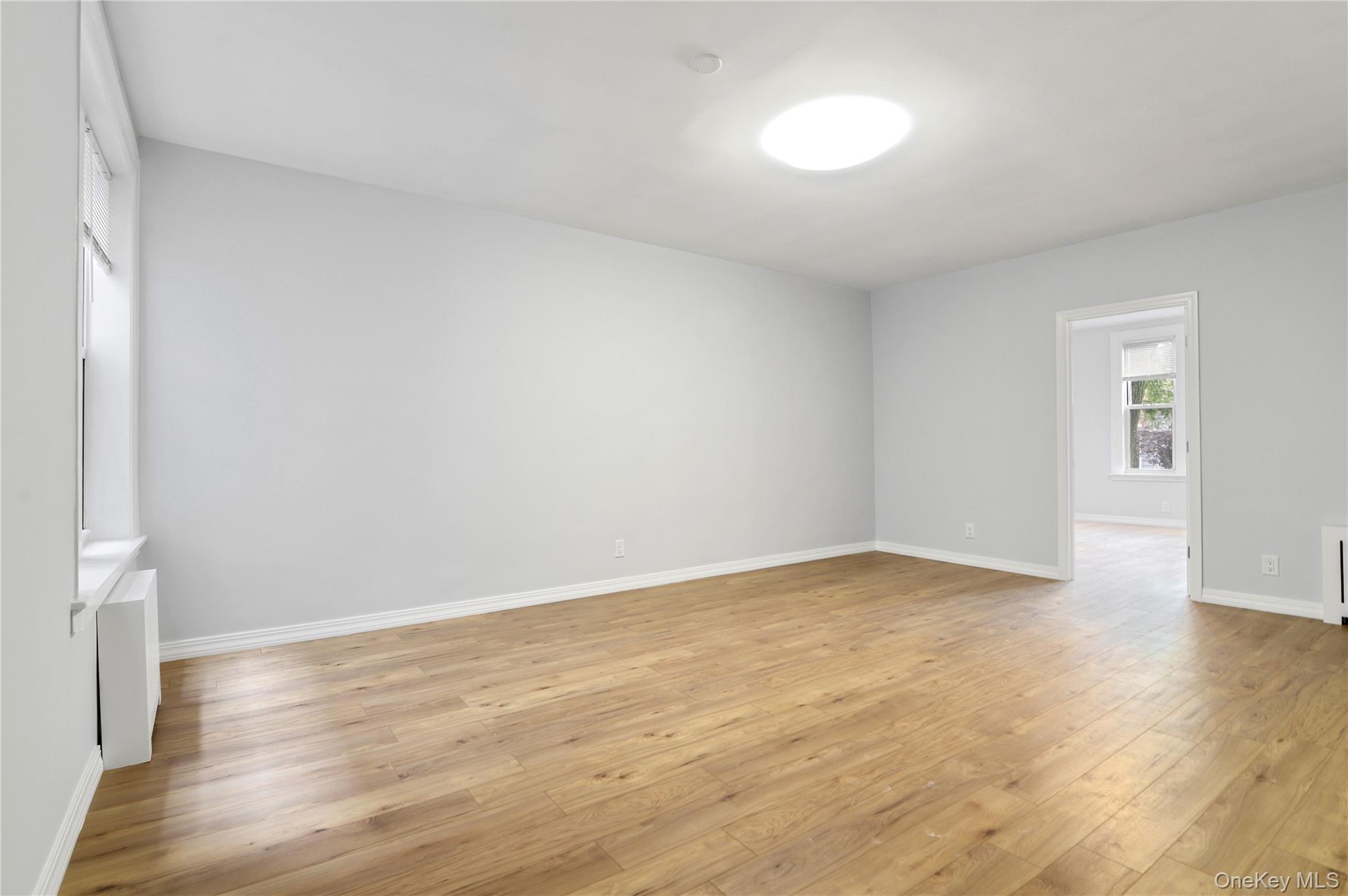 21-69 45th Street, Unit 3 Queens, NY 11105 - Photo 8 of 31 an empty room with wooden floor and windows