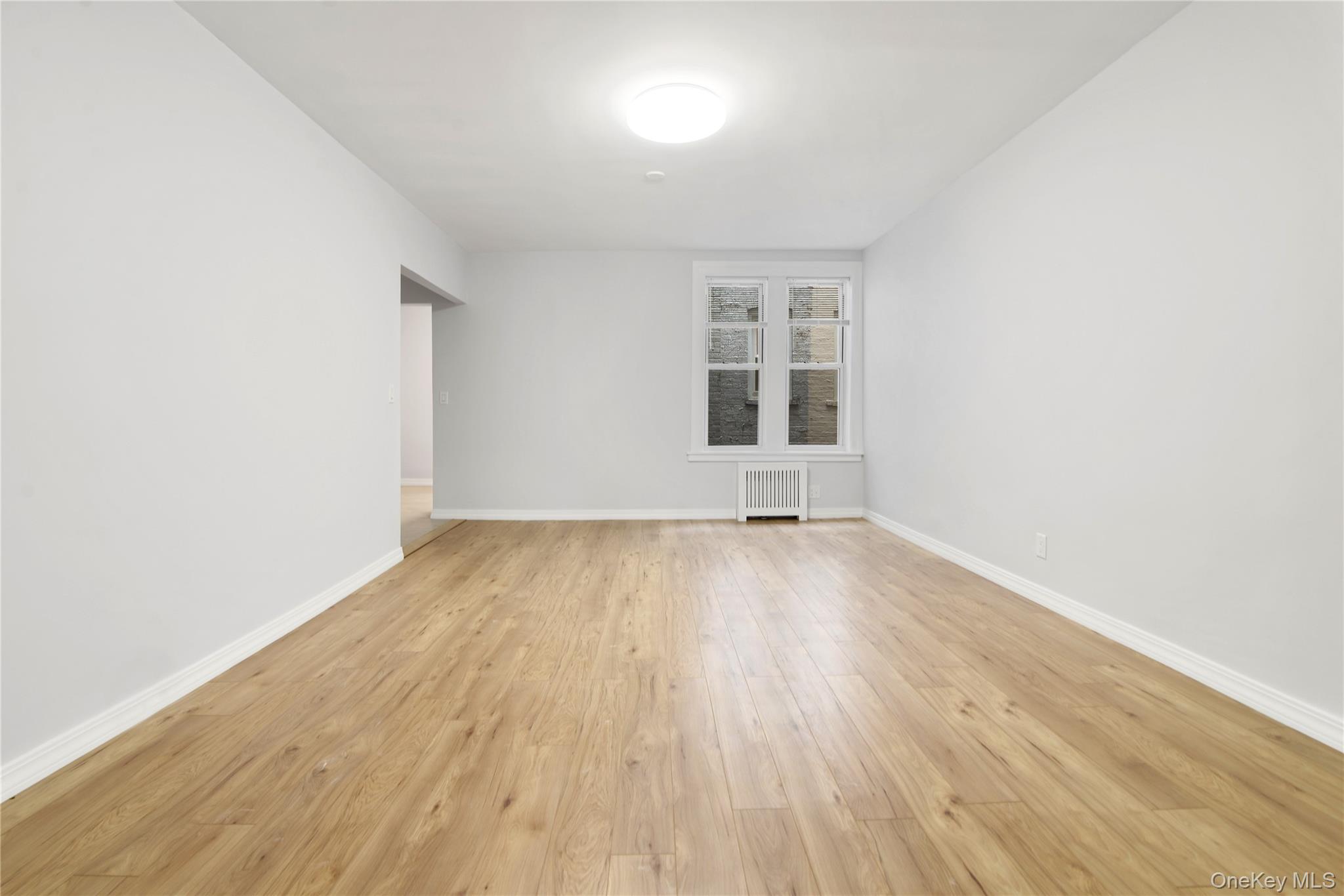 21-69 45th Street, Unit 3 Queens, NY 11105 - Photo 9 of 31 an empty room with wooden floor and windows