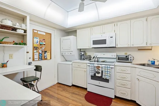 a kitchen with stainless steel appliances granite countertop a stove a sink dishwasher and white cabinets with wooden floor