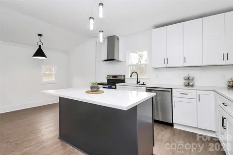a kitchen with stainless steel appliances granite countertop a sink stove and white cabinets with wooden floor