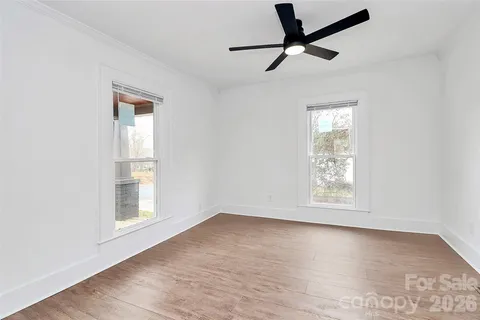 an empty room with wooden floor fan and windows