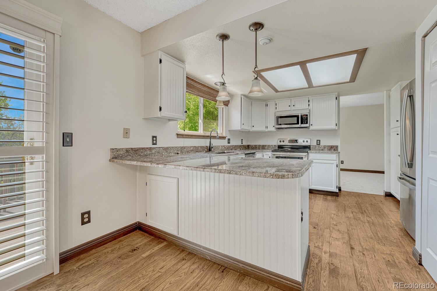 302 Northridge Road Highlands Ranch, CO 80126 - Photo 11 of 36 a kitchen with kitchen island granite countertop a sink cabinets and wooden floor