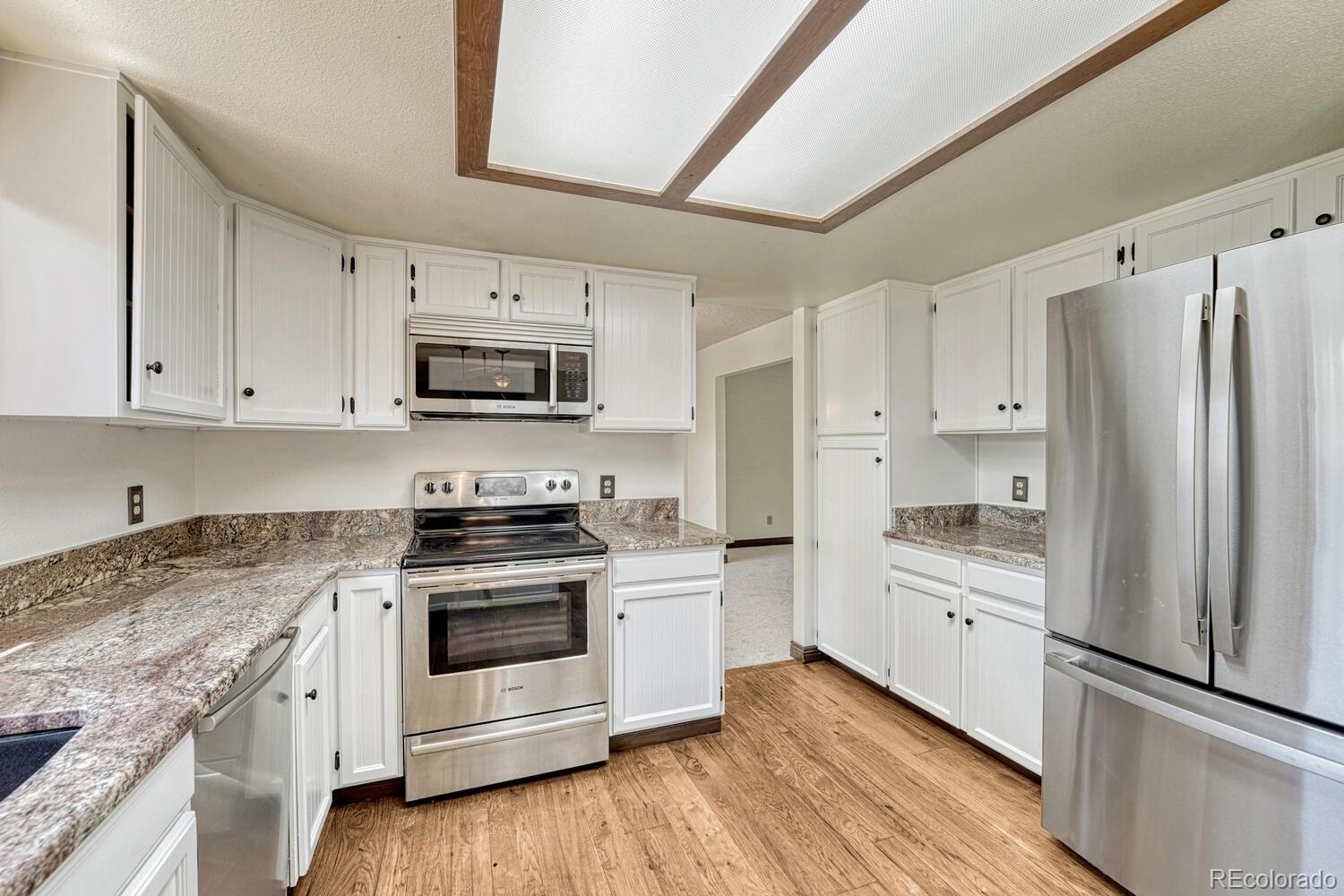 302 Northridge Road Highlands Ranch, CO 80126 - Photo 12 of 36 a kitchen with granite countertop white cabinets and stainless steel appliances