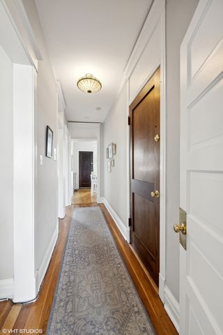 a view of a hallway with wooden floor and a bathroom