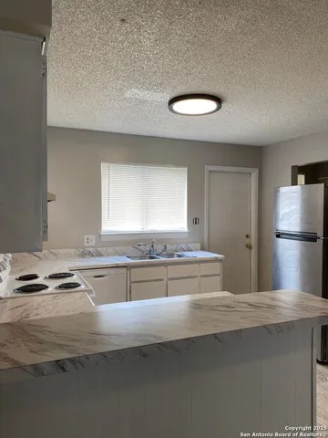 a kitchen with kitchen island granite countertop a sink cabinets and stainless steel appliances
