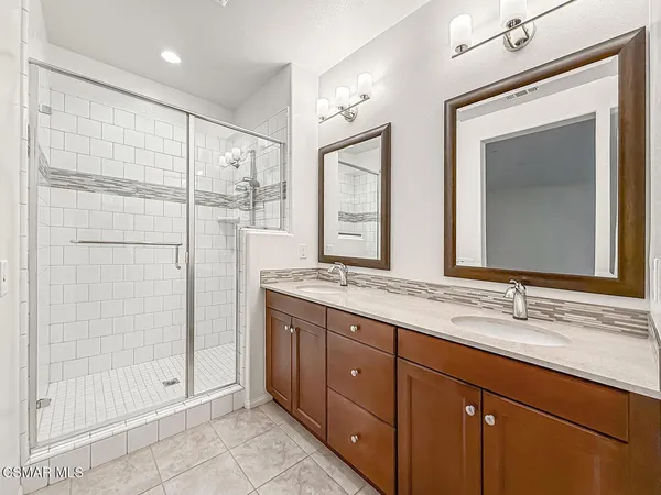a bathroom with a double vanity sink mirror and shower