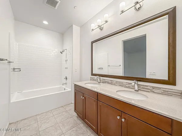 a bathroom with a tub a sink and mirror
