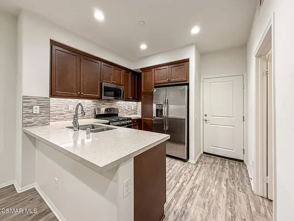 a kitchen with a sink a refrigerator a microwave and cabinets