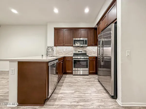 a kitchen with stainless steel appliances granite countertop a stove a sink and a refrigerator