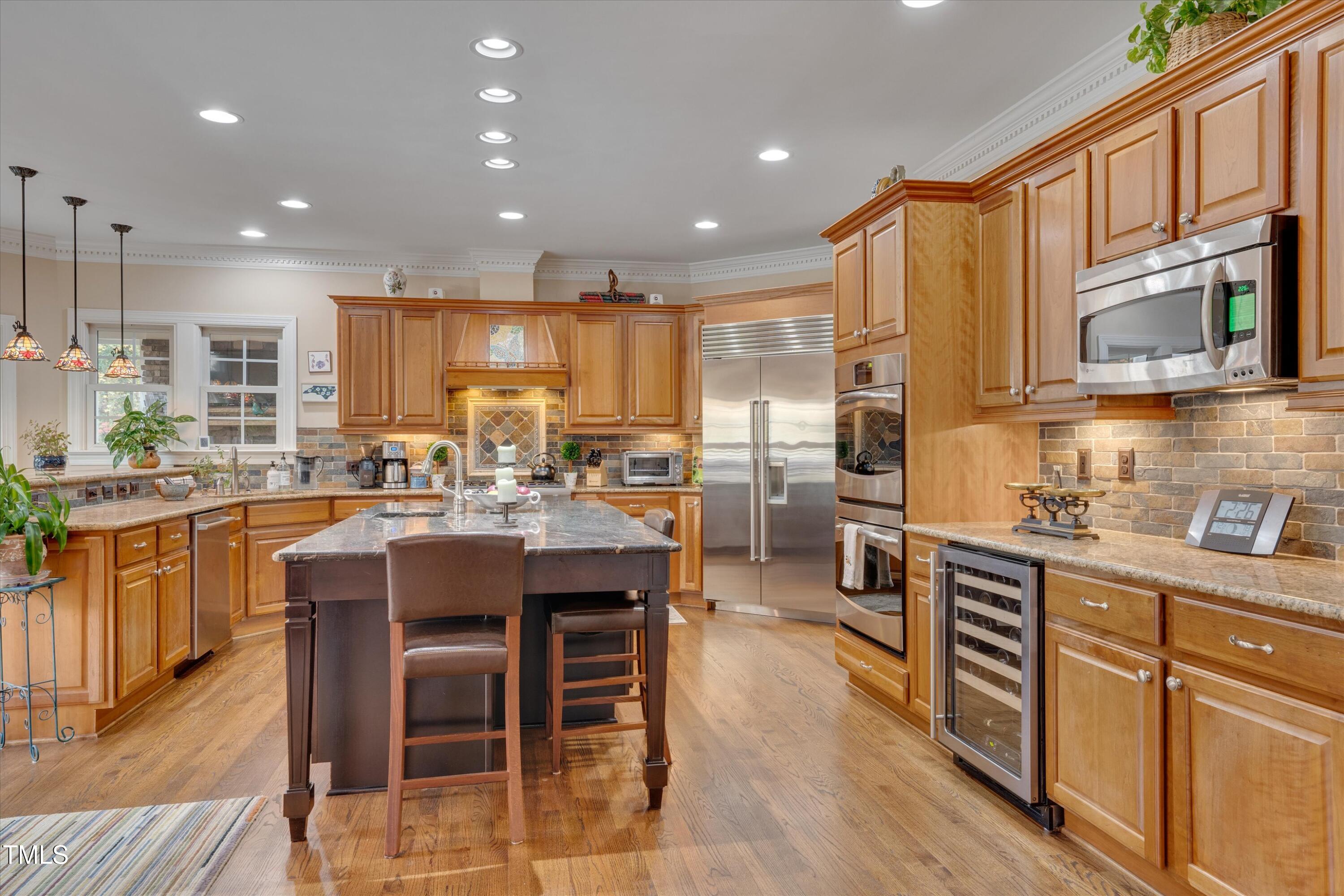 8308 Cazavini Court Raleigh, NC 27613 - Photo 8 of 46 a kitchen with stainless steel appliances kitchen island granite countertop a stove a sink a refrigerator dining table and chairs