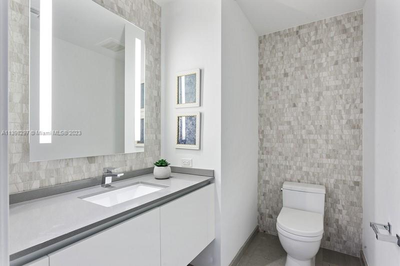68 Southeast 6th Street, Unit 1209 Miami, FL 33131 - Photo 12 of 15 a bathroom with a granite countertop sink toilet and a mirror