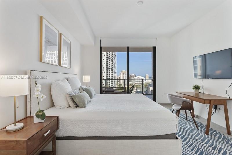 68 Southeast 6th Street, Unit 1209 Miami, FL 33131 - Photo 7 of 15 a bedroom with a bed and a table in it