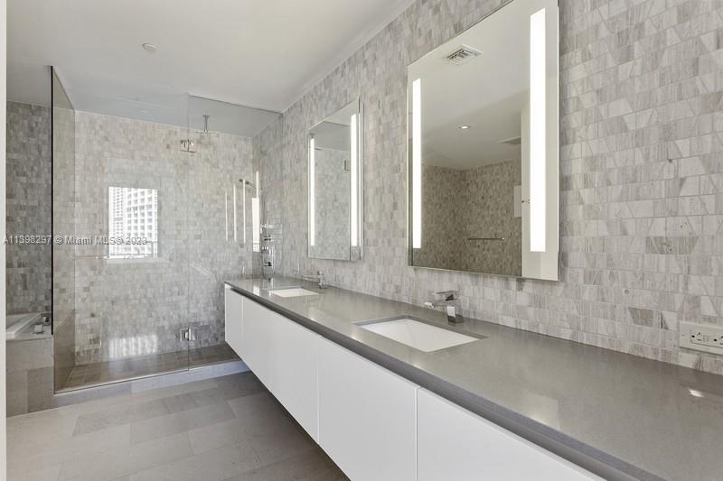 68 Southeast 6th Street, Unit 1209 Miami, FL 33131 - Photo 9 of 15 a bathroom with a double vanity sink a mirror and a shower