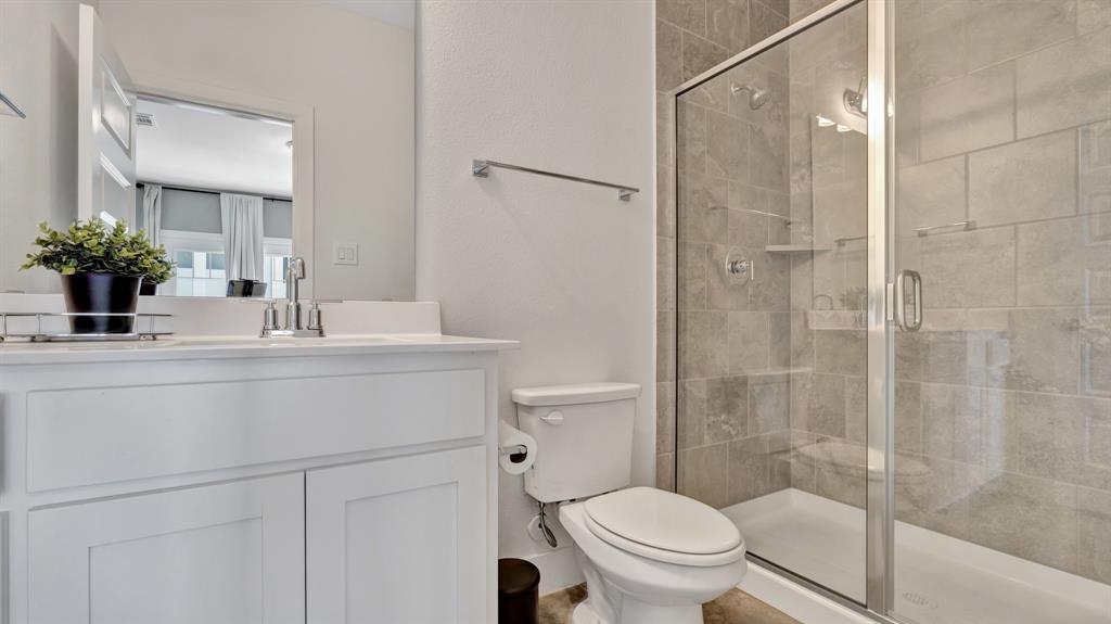 602 Winners Circle Rowlett, TX 75088 - Photo 26 of 35 Secondary bedroom, ensuite, featuring a glass-enclosed shower with tile surround, white vanity with integrated sink, and contemporary fixtures