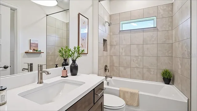 a bathroom with a granite countertop bathtub sink vanity mirror and toilet