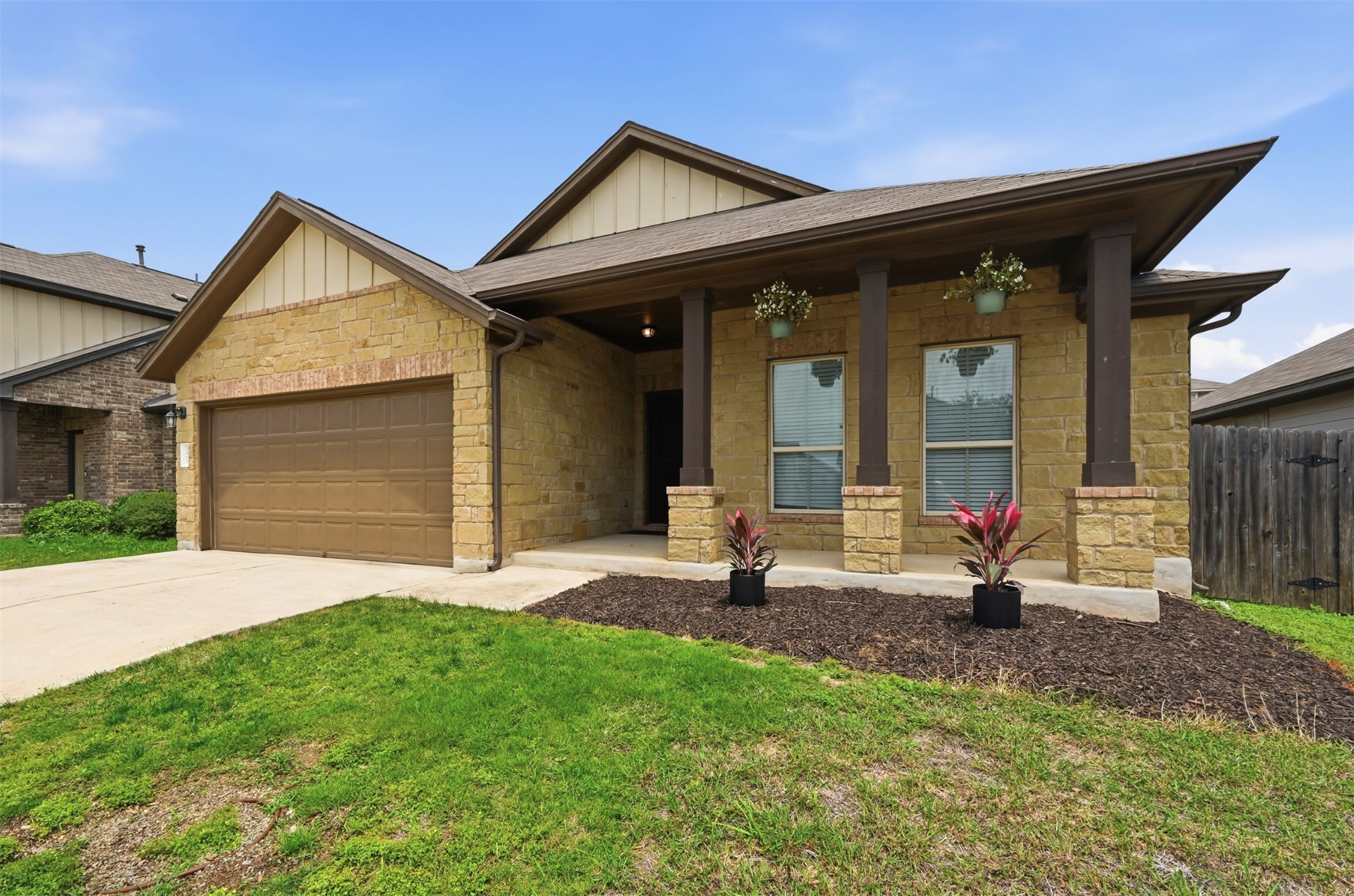 303 Limerick Road Buda, TX 78610 - Photo 22 of 23 Stone veneer facade with a covered entry, featuring a single-car garage with a brown door