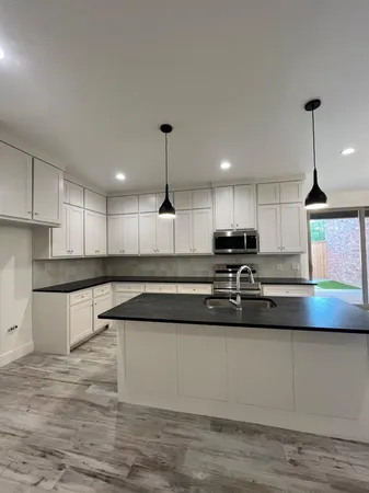 a kitchen with granite countertop white cabinets stainless steel appliances and sink