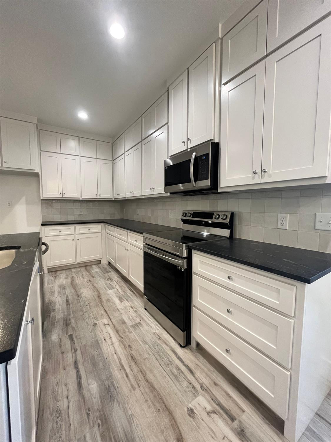 5102 58th Street, Unit 2 Lubbock, TX 79414 - Photo 6 of 18 a kitchen with granite countertop white cabinets stainless steel appliances and sink