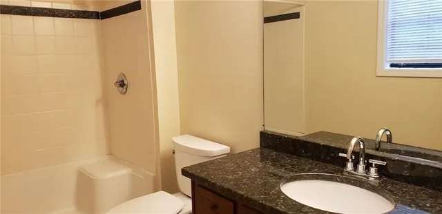 a bathroom with a granite countertop sink toilet and shower
