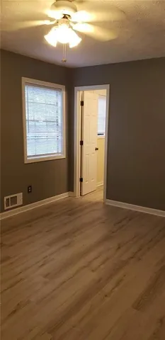 a view of an empty room with window and wooden floor