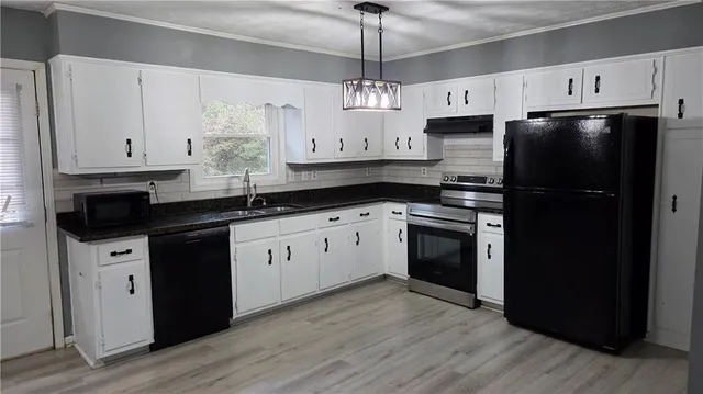 a kitchen with stainless steel appliances granite countertop a refrigerator a sink dishwasher a stove and white cabinets