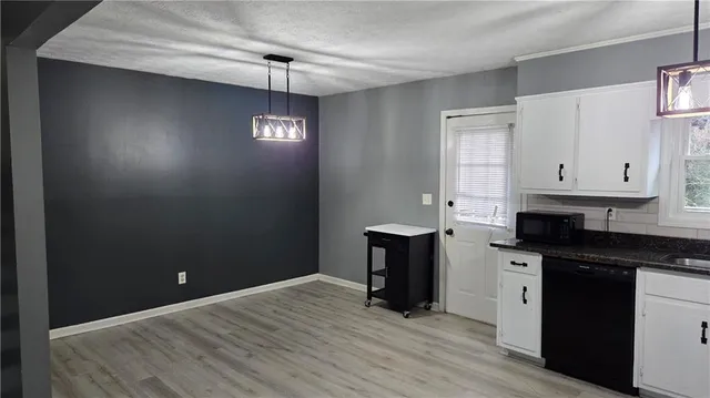 a kitchen with granite countertop white cabinets and black appliances