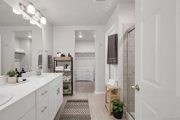 a spacious bathroom with a double vanity sink a large mirror and shower