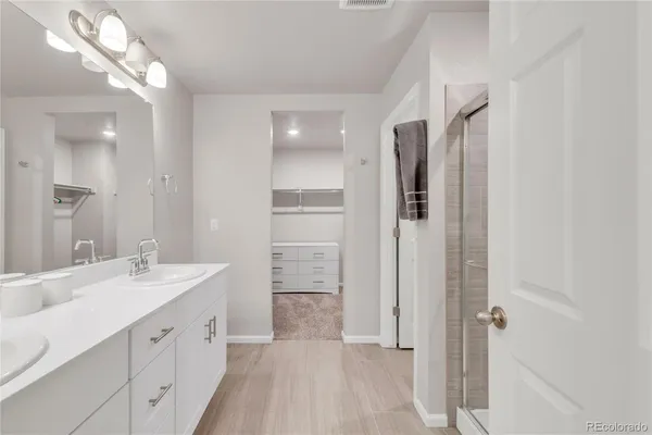 a spacious bathroom with a double vanity sink a large mirror and shower