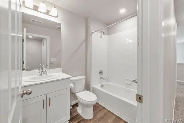a bathroom with a bathtub shower sink vanity mirror and toilet
