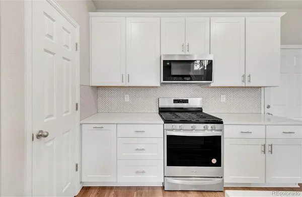 a kitchen with white cabinets and a stove with a sink