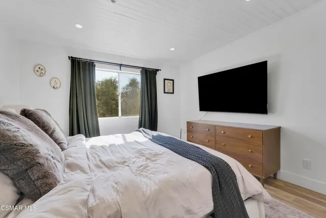 a bedroom with a bed tv and a window