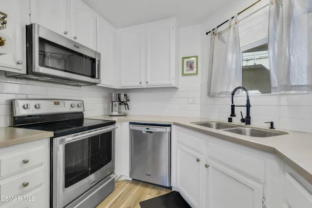 a kitchen with stainless steel appliances granite countertop grey cabinets a stove a sink and dishwasher