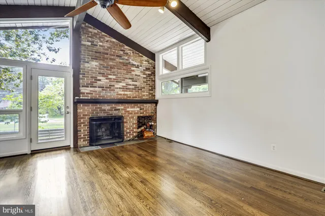 an empty room with wooden floor fireplace and windows