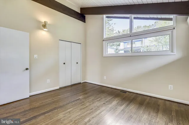a view of an empty room with a window and wooden floor