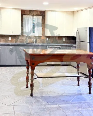 a kitchen with kitchen island a stove a sink and white cabinets