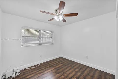 an empty room with wooden floor and ceiling fan
