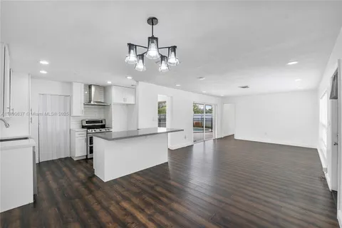 a kitchen with stainless steel appliances granite countertop a sink a stove a refrigerator and a sink with wooden floor