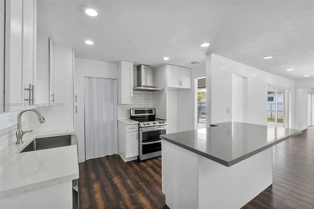 a large kitchen with stainless steel appliances granite countertop a sink a stove and a refrigerator