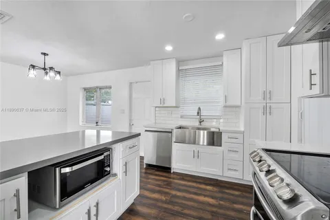 a kitchen with stainless steel appliances kitchen island granite countertop a sink stove and refrigerator
