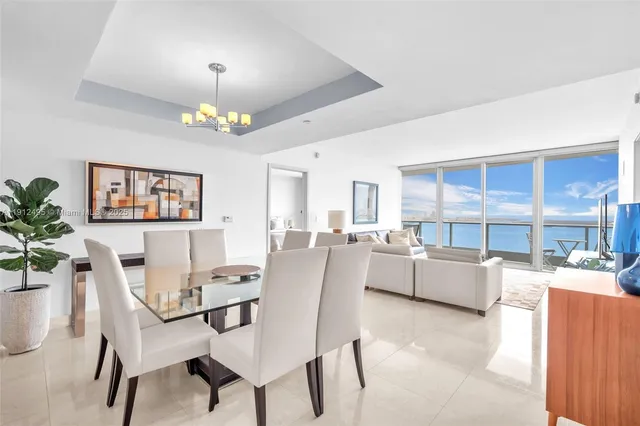a dining room with furniture a kitchen and chandelier