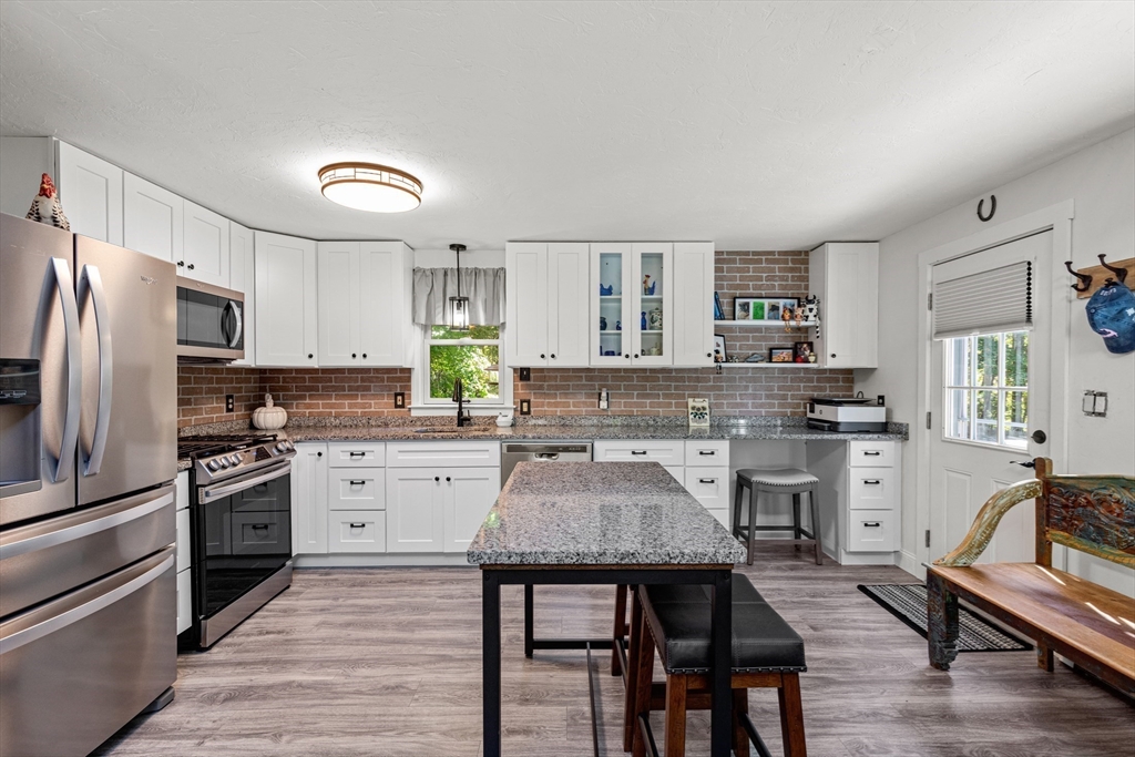 901 Head Of The Bay Road Bourne, MA 02532 - Photo 5 of 20 a kitchen with stainless steel appliances a stove a sink dishwasher a refrigerator white cabinets and wooden floor