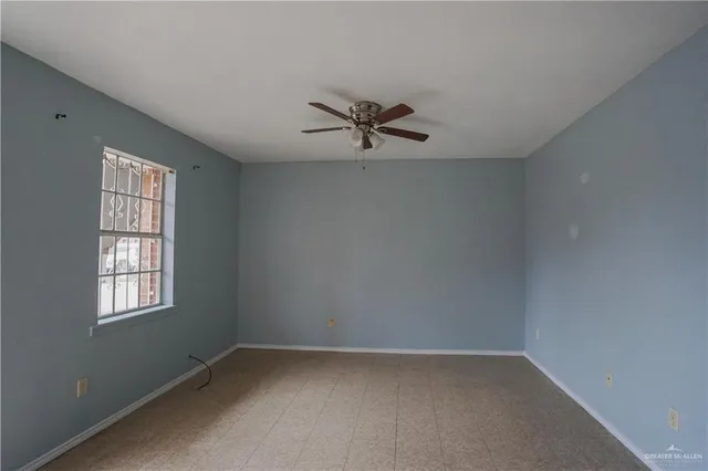 an empty room with windows and ceiling fan