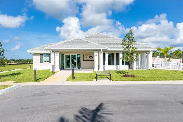 a view of yellow house with a big yard and large trees
