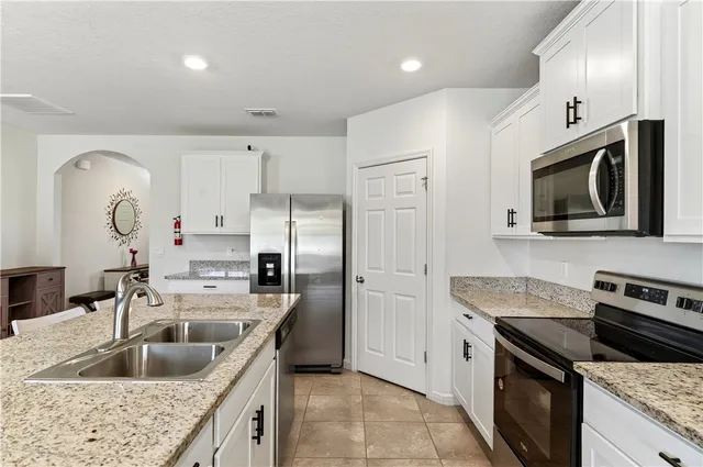 a kitchen with granite countertop a sink stainless steel appliances and cabinets