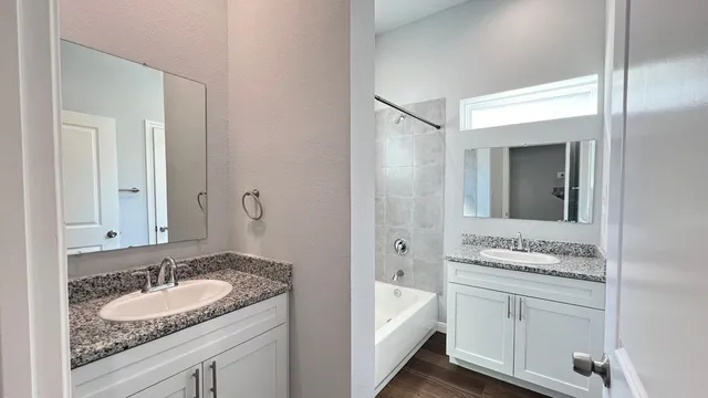 a bathroom with a granite countertop tub sink and mirror