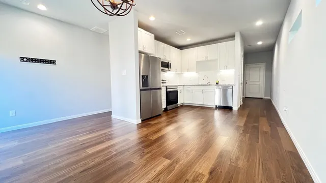 a large kitchen with a wooden floor and stainless steel appliances